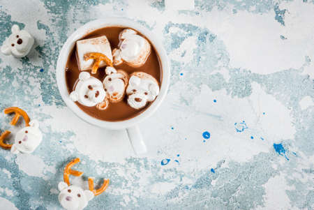 Idea for a children's Christmas snack, hot chocolate with teddy bears and deer marshmallow. On a light blue background, copy space top viewの写真素材