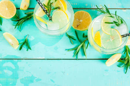Cold lemonade or alcohol vodka cocktail with lemon and rosemary, on light blue table, copy space top viewの写真素材
