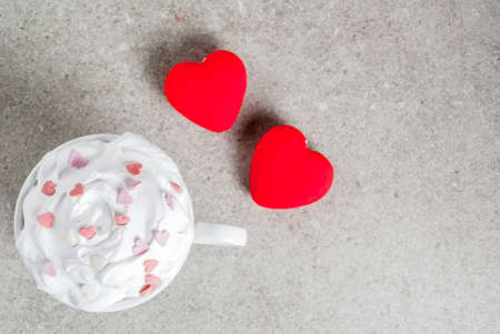 Romantic background, Valentine's day. Cup for coffee or hot chocolate, with whipped cream and sweet hearts, with two plush red hearts,  copy space top viewの写真素材