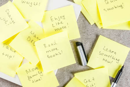 New years resolutions, grey stone table with colorful sticky notes with popular new year resolutions and pen, copy spaceの写真素材
