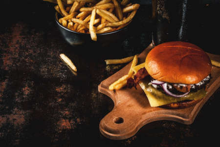 Fresh meat and cheese burger with French fries and glass of dark ginger beer, on dark blue background, copy spaceの写真素材