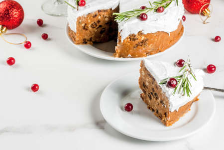 Christmas fruit cake or pudding, decorated with rosemary and cranberry, with christmas decoration, on white marble table, copy spaceの写真素材