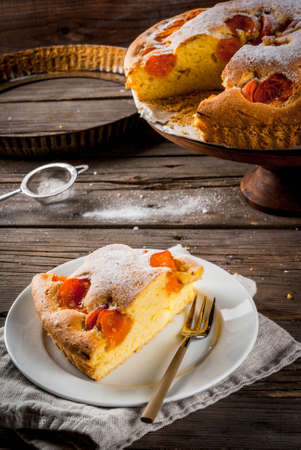 Homemade autumn and summer baked pastries. Sponge cake with apricots. Cut into pieces, plate, fork. On the stand. On the old wooden rustic table. Copy spaceの写真素材