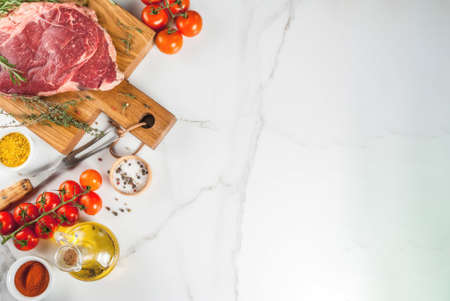 Fresh raw meat, lamb beef marble steak on a cutting board, with ingredients for cooking. On white...