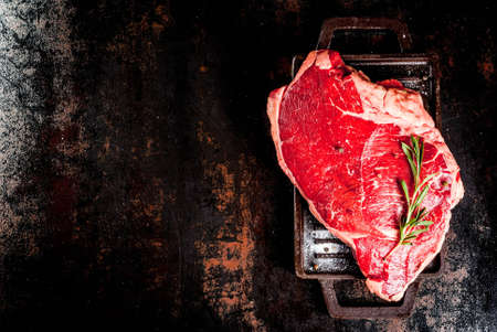 Fresh raw meat, lamb beef marble steak on a grill pan board, with ingredients for cooking. On dark rusty metal table, copy space top viewの写真素材