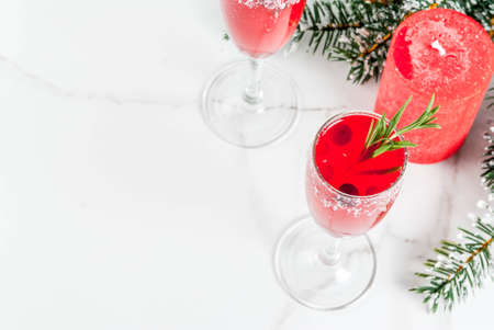 Christmas morning red cranberry mimosa with rosemary, white marble background copy space with christmas decorations top viewの写真素材