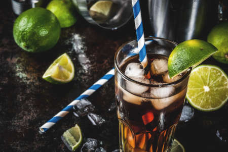 Cuba Libre, long island or iced tea cocktail with strong alcohol, cola, lime and ice, two glass, dark background copy spaceの写真素材