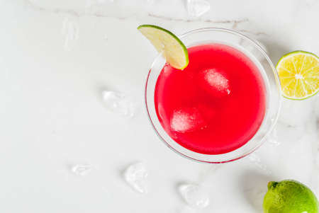 Red cosmopolitan cocktail with lime in martini glass, on white marble background copy space top viewの写真素材