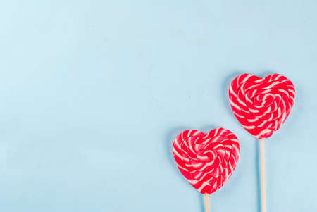 Valentine's day light blue background, greeting card concept, Two red heart lollipops or sweet candy on sticks,  top view copy spaceの写真素材