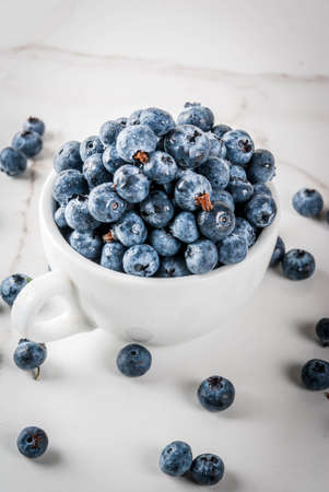 Fresh raw organic farm blueberry in white cup on white marble kitchen background, copy spaceの写真素材