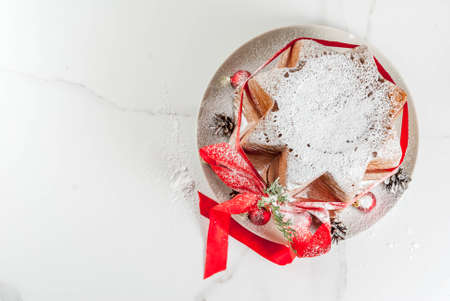 Traditional Italian Christmas fruit cake Panettone Pandoro with festive red ribbon and Christmas decorations, on white background, copy space top viewの写真素材