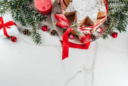 Traditional Italian Christmas fruit cake Panettone Pandoro with festive red ribbon and Christmas decorations, on white background, copy space top viewの写真素材