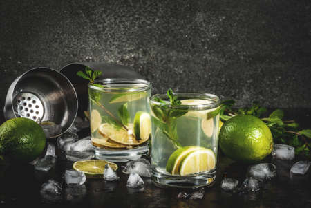Homemade lemonade or mojito cocktail with fresh lime and mint leaves, dark rusty metal background,...