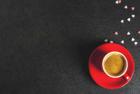 Valentine's day concept, coffee mug and sweet heart shaped sprinkles, black background, copy space ...