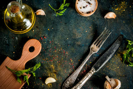 Cooking food concept, spices, herb and oil for preparing dinner, with cutting board, table knife and fork, copy space top view frameの写真素材