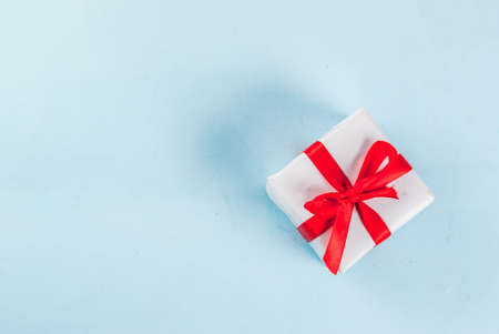 Valentine's day light blue background with gift box with red ribbon. Greeting card concept. Top view copy spaceの写真素材