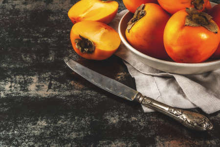 Delicious raw ripe persimmon fruit on dark rusty metal background copy spaceの写真素材