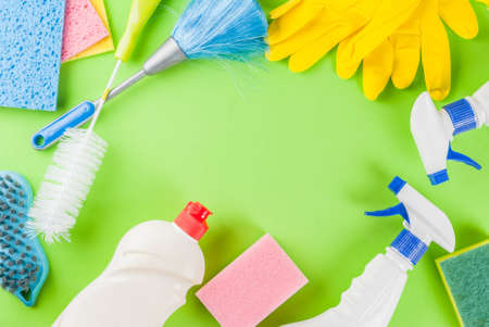 Spring cleaning concept with supplies, house cleaning products pile. Household chore concept, on green background top view copy space frameの写真素材
