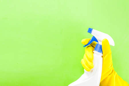 Hand in protective glove holding spray. green background copy spaceの写真素材