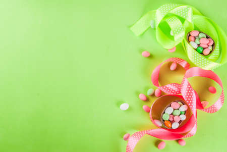 Easter holiday greeting card background, with chocolate easter bunny, candy eggs, quail eggs and festive ribbon, copy space top viewの写真素材