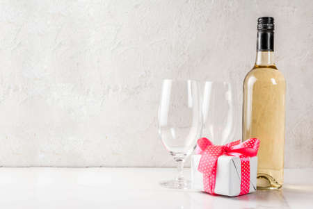 Valentines day concept with wine, two glasses and gift box on white concrete background, copy spaceの写真素材