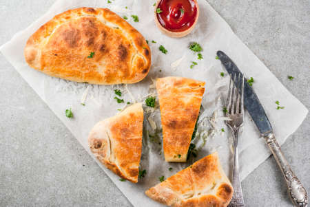 Italian food, closed pizza calzone with Spinach and Cheese, gray stone background, copy space top viewの写真素材