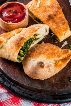 Italian food, closed pizza calzone with Spinach and Cheese, wooden background, copy spaceの写真素材