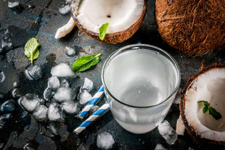 Healthy food concept.  Fresh Organic Coconut Water with coconuts, ice cubes and mint, on rusty dark...