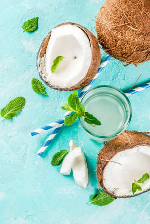 Healthy food concept.  Fresh Organic Coconut Water with coconuts, ice cubes and mint, on light blue background, copy space top viewの写真素材