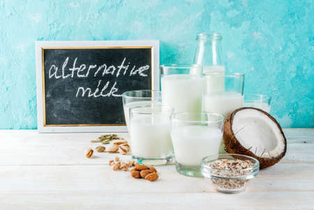 Vegan alternative food, set of various non-dairy milk - rice, coconut, almonds, pistachio, sesame, pumpkin seeds, soy, nuts, oatmeal, on light blue background, copy spaceの写真素材