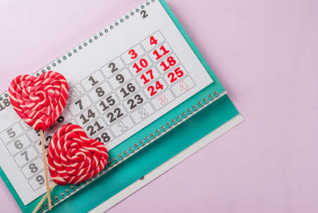 Valentine's day light pink background, greeting card concept, Two red heart lollipops or sweet candy...