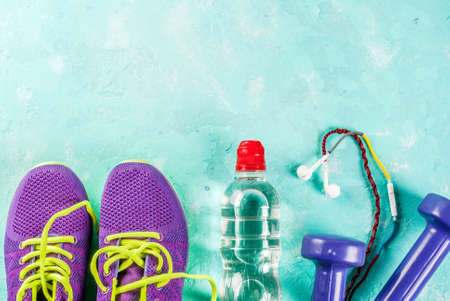 Sports, fitness concept. Running sneakers, water bottle, headphones, dumbbells, smartphone, on a light blue background top view copy spaceの写真素材