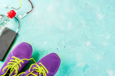 Sports, fitness concept. Running sneakers, water bottle, headphones, dumbbells, smartphone, on a light blue background top view copy spaceの写真素材