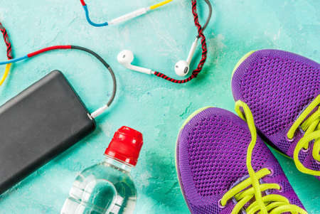 Sports, fitness concept. Running sneakers, water bottle, headphones, dumbbells, smartphone, on a...