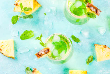 Tropical drink, Pineapple juice margarita cocktail with fresh mint, light blue background copy space top viewの写真素材