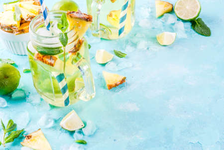 Tropical drink,  Pineapple mojito or lemonade with fresh lime and mint  light blue background, copy...