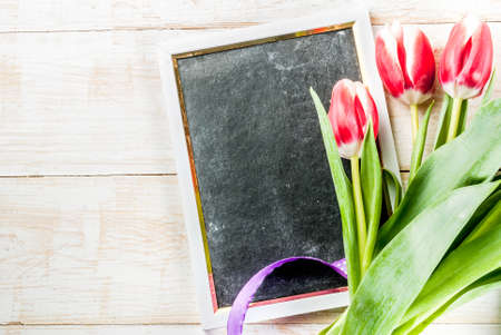 Background for congratulations, greeting cards. Fresh spring tulips flowers with chalkboard for...