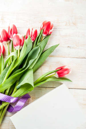 Background for congratulations, greeting cards. Fresh spring tulips flowers, on white wooden background top view copy spaceの写真素材