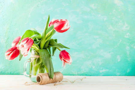 Spring concept. Flowers tulips in a glass mason jar, on a light blue and wooden white background. Copy spaceの写真素材