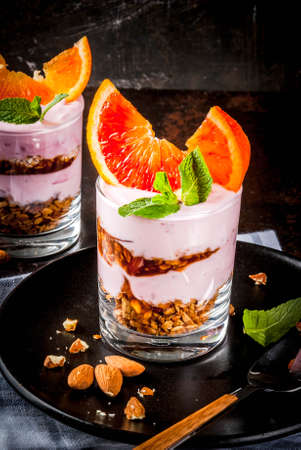 Healthy breakfast, Blood Orange Parfait with granola. yogurt, almond and mint, dark rusty background, copy spaceの写真素材