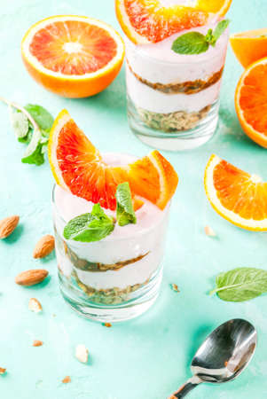 Healthy breakfast, Blood Orange Parfait with granola. yogurt, almond and mint, light blue background, copy spaceの写真素材