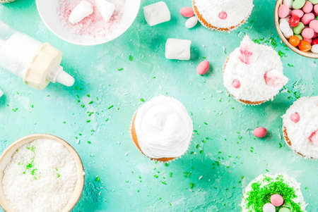 Making easter cupcakes with bunny ears and candy eggs, copy space top viewの写真素材