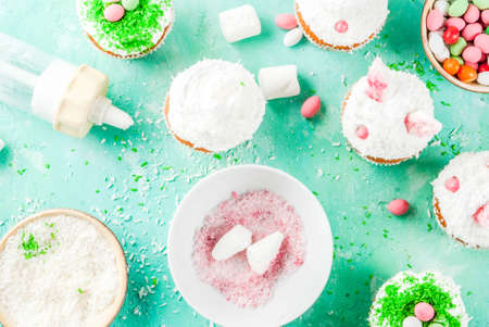 Making easter cupcakes with bunny ears and candy eggs, copy space top view