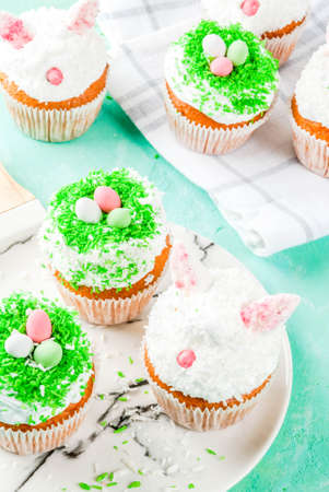 Easter cupcakes with bunny ears and candy eggs, copy space