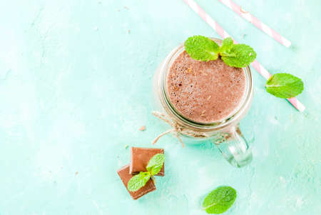 Chocolate smoothie or milkshake with mint and straw, in mason jar on light blue background, copy space top viewの写真素材