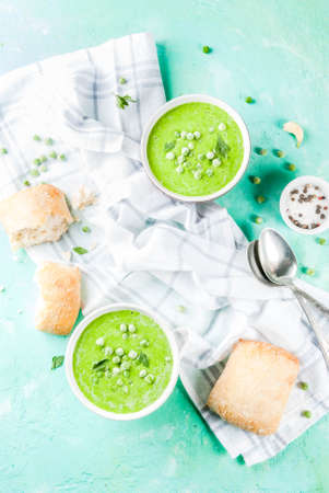 Green pea soup with fresh bread on light blue concrete table, copy space top viewの写真素材