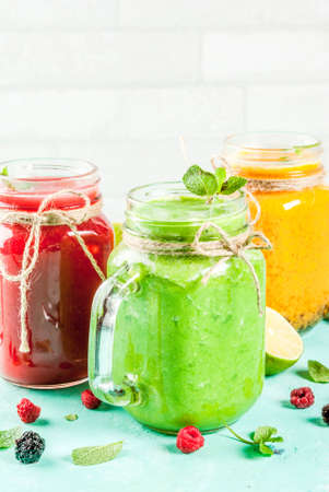 Healthy fresh fruit and veggie smoothies with ingredients on light blue concrete table, copy spaceの写真素材
