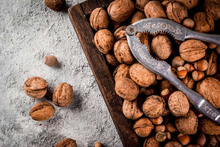 Various nuts and nutcracker in wooden box. On rustic grey stone table, copy spaceの写真素材