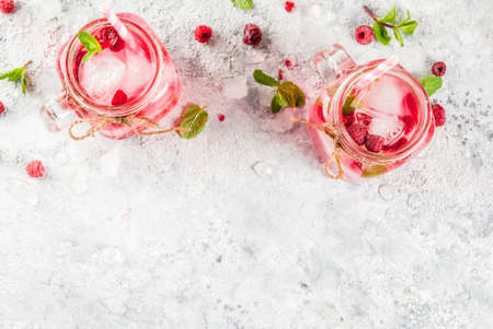 Cold summer drink, Raspberry Sangria, Lemonade or Mojito with fresh Raspberry and syrup, mint leaves, on grey stone background copy space top viewの写真素材