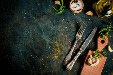 Cooking food concept, spices, herb and oil for preparing dinner, with cutting board, table knife and fork, copy space top viewの写真素材